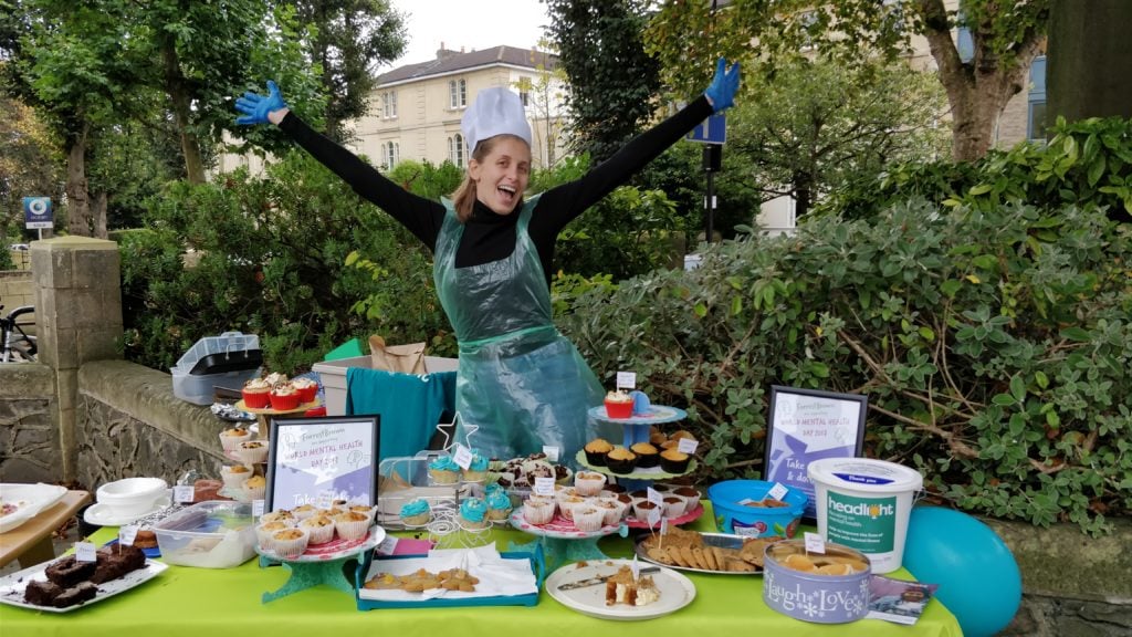 Woman surrounded by cakes at charity bake sale